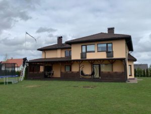 Kollane elumaja uue pruuni kivikatusega Rohelise muruplatsi peal.