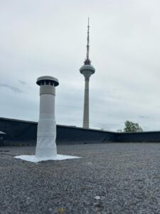 Hallil SBS-bituumen lamekatusel valge vedelplastiga remonditud korsten, tagaplaanil on Tallinna Teletorni